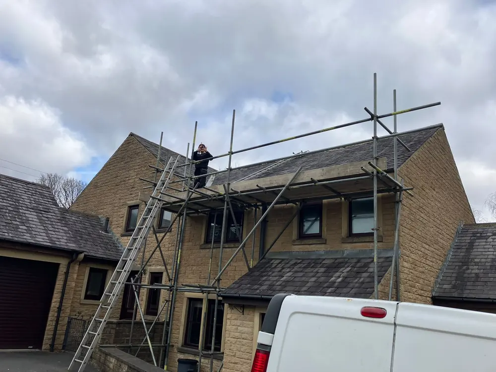 Ladder and scaffold access set up against a stone house in Halifax ready for roof works